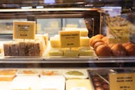 A variety of Indian desserts including milk cake, coconut barfi, and ladoo displayed in a café.